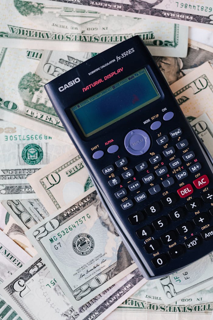 Scientific calculator placed on various US dollar bills, symbolizing finance and calculation concepts.